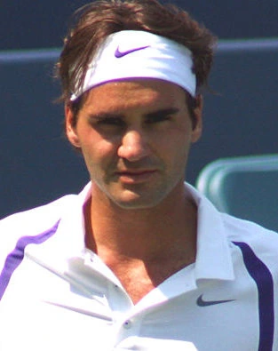 Roger Federer lors d’un match de tennis, en tenue blanche sur gazon.