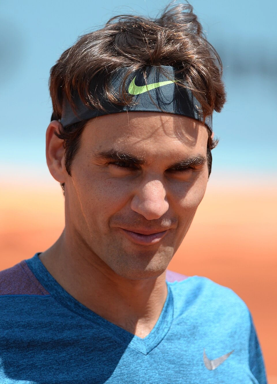 Roger Federer en portrait, portant un bandeau Nike et un haut bleu, regard vers l’objectif.